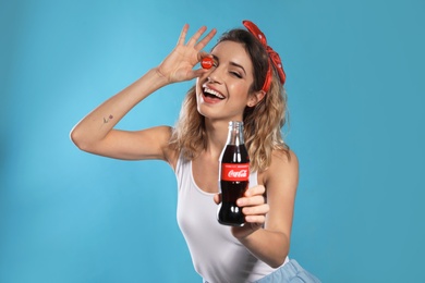 MYKOLAIV, UKRAINE - NOVEMBER 28, 2018: Young woman with bottle of Coca-Cola and cap on color background