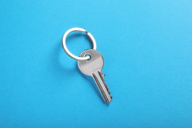 Photo of Key on blue background, top view. Real estate agent services