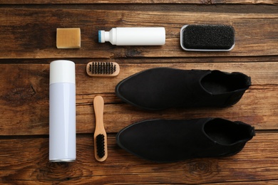 Stylish footwear with shoe care accessories on wooden table, flat lay