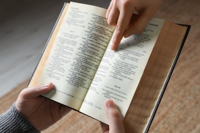 Woman showing psalm in Bible to man indoors, closeup