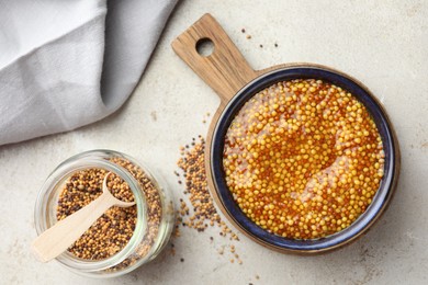 Photo of Whole grain mustard and dry seeds on white table, flat lay