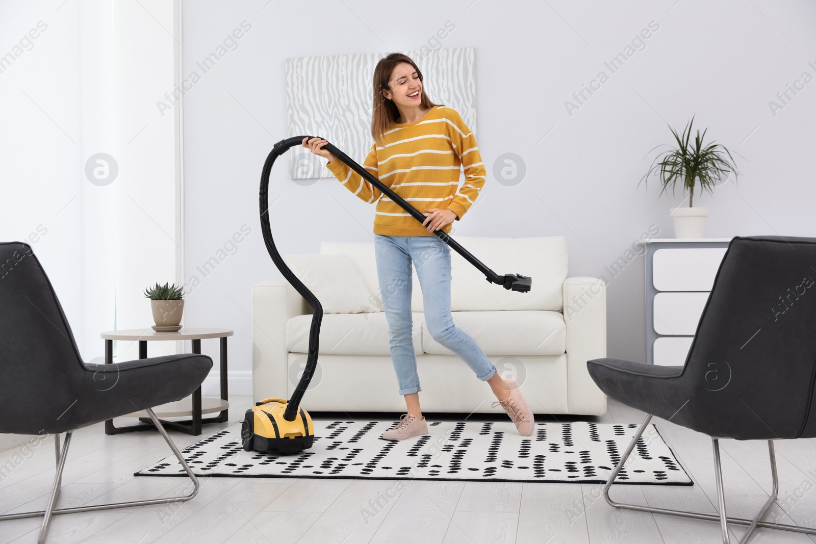 Photo of Young woman having fun while vacuuming at home