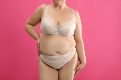 Photo of Overweight woman in beige underwear on pink background, closeup. Plus-size model