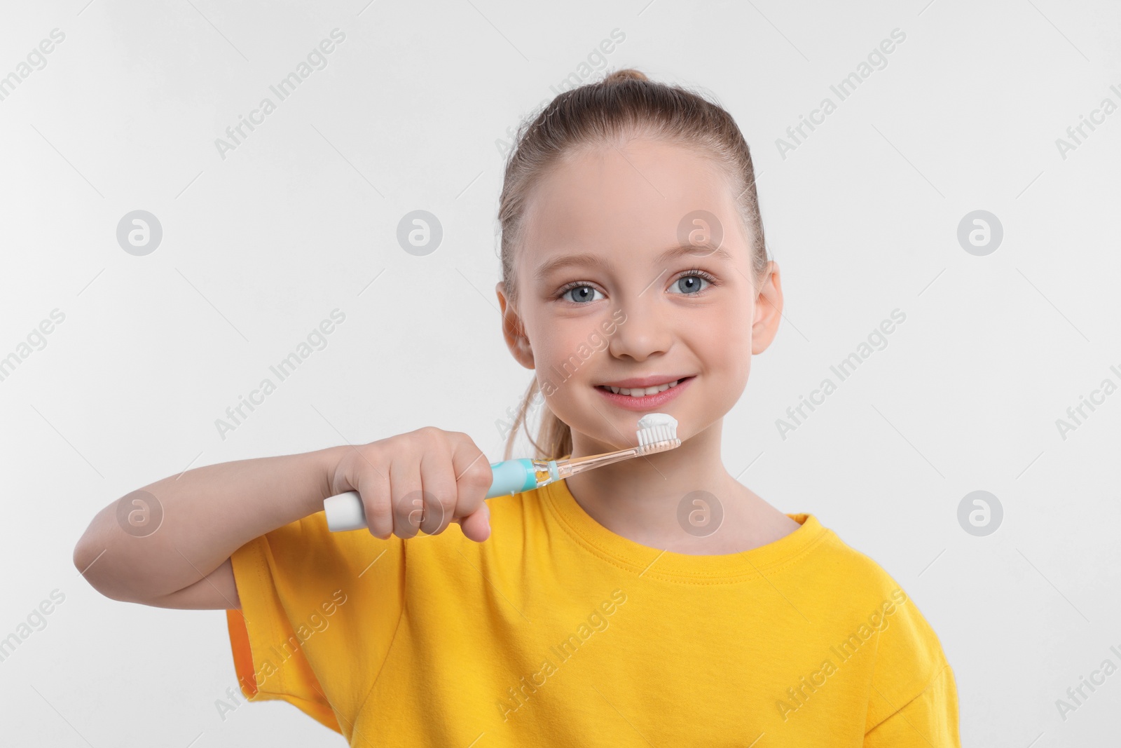 Photo of Happy girl brushing her teeth with electric toothbrush on white background