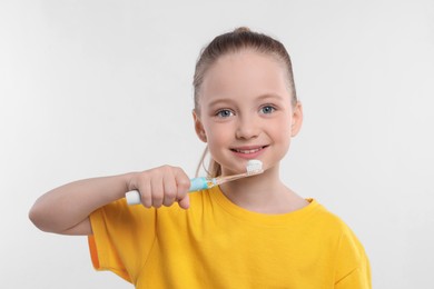 Photo of Happy girl brushing her teeth with electric toothbrush on white background