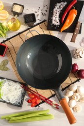 Photo of Wok, chopsticks and different products on white wooden table, flat lay