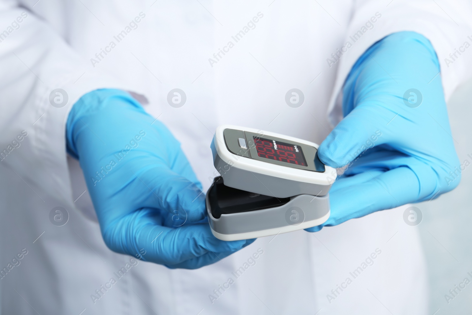 Photo of Doctor holding modern fingertip pulse oximeter, closeup