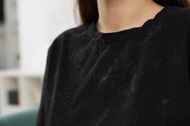 Photo of Woman with pet hair on her black clothers indoors, closeup