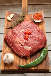 Photo of Fresh raw beef cut with spices on wooden table