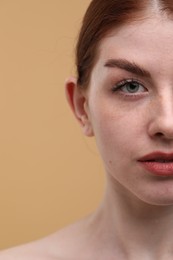 Photo of Beautiful woman with freckles on beige background, closeup