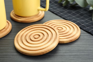 Stylish wooden cup coasters and mugs on black table