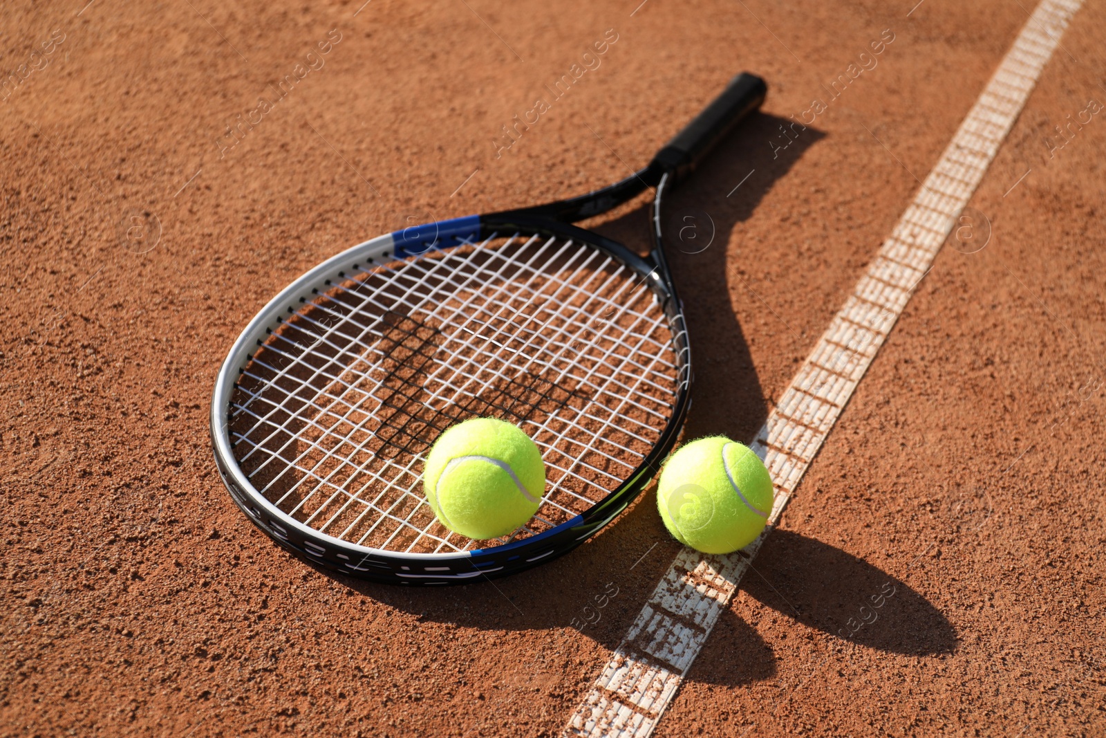 Photo of Tennis balls and racket on clay court