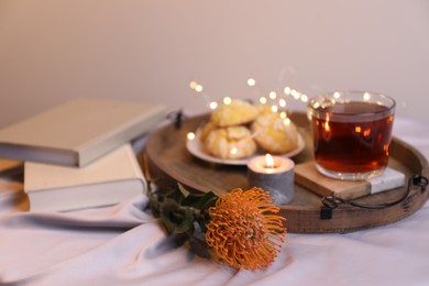 Photo of Composition with beautiful leucospermum flower, tasty tea and books. Cozy home atmosphere