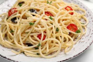 Delicious pasta with olives, tomatoes and parmesan cheese on white table, closeup