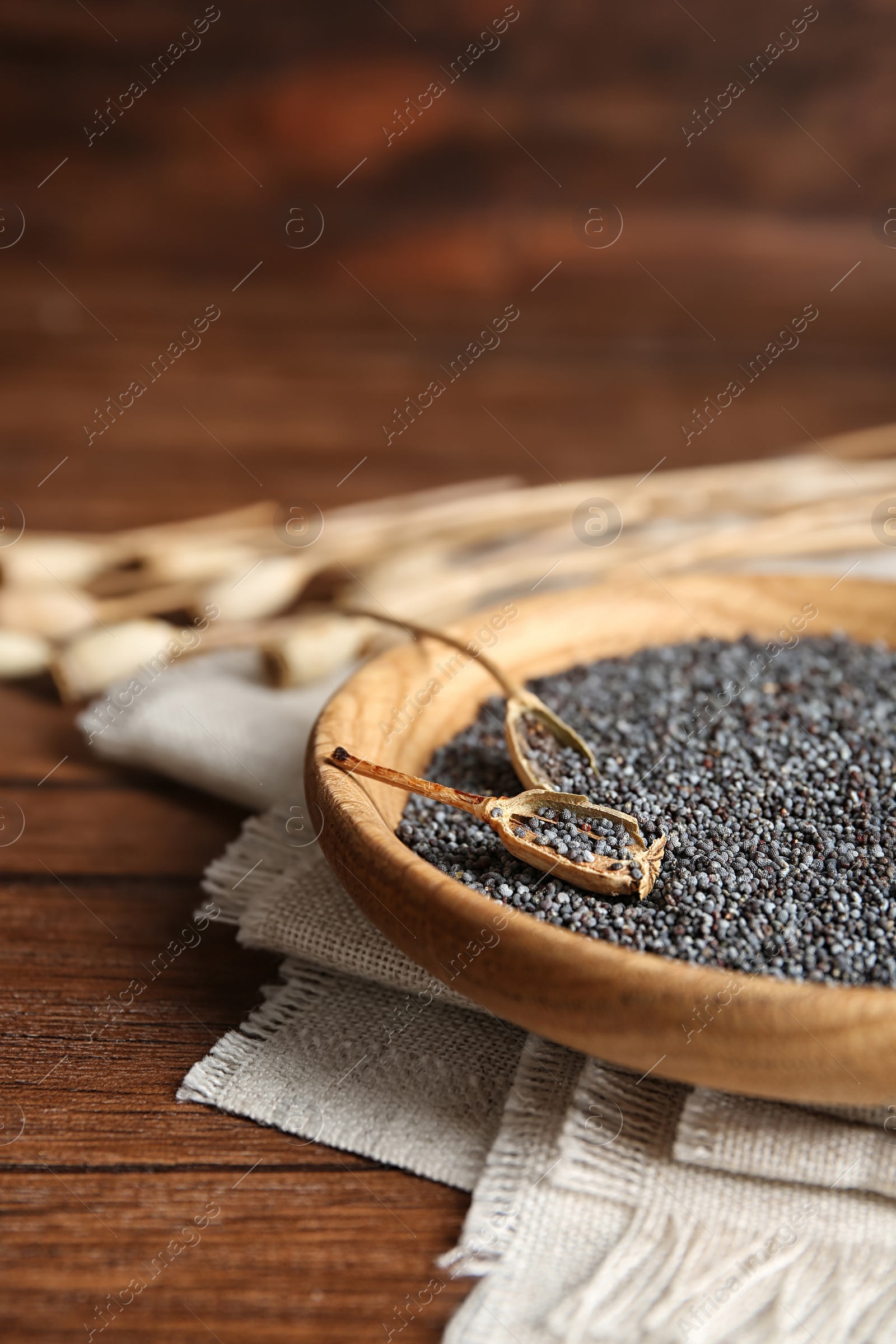 Photo of Plate with poppy seeds on wooden table