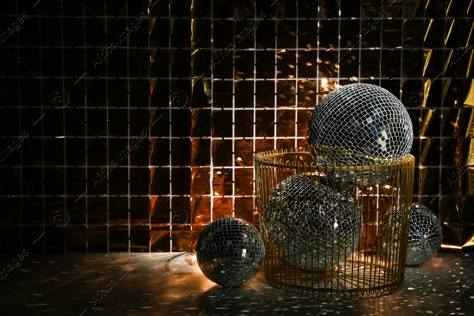 Photo of Many shiny disco balls on floor near foil party curtain. Space for text