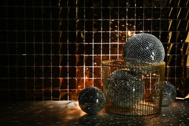 Many shiny disco balls on floor near foil party curtain. Space for text