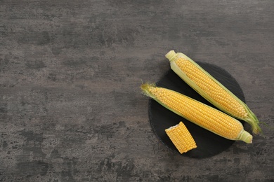 Plate with tasty sweet corn cobs on table, top view