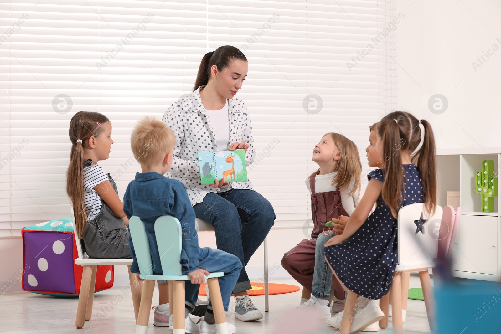 Photo of Nursery teacher and group of cute little children learning animals in kindergarten. Playtime activities