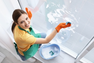 Young woman cleaning window glass at home