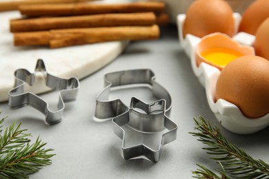 Photo of Cookie cutters and eggs on light grey table, closeup. Christmas biscuits