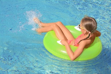 Cute little girl with inflatable ring in pool on sunny day