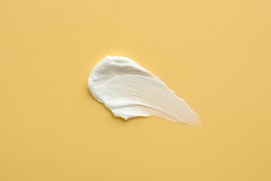 Sample of face cream on yellow background, top view