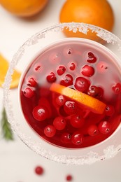 Photo of Tasty cranberry cocktail in glass on white table, flat lay