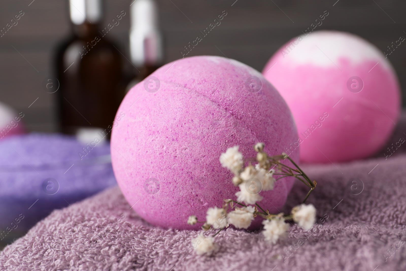 Photo of Beautiful aromatic bath bomb and gypsophila flowers on soft towel, closeup