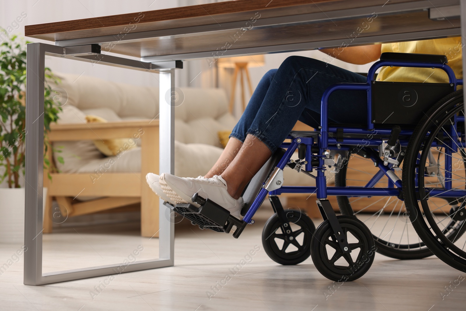 Photo of Woman in wheelchair at table indoors, closeup