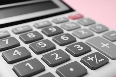 Calculator on pink background, closeup. Office equipment