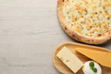 Photo of Delicious cheese pizza and different kinds of cheese on wooden table, flat lay. Space for text