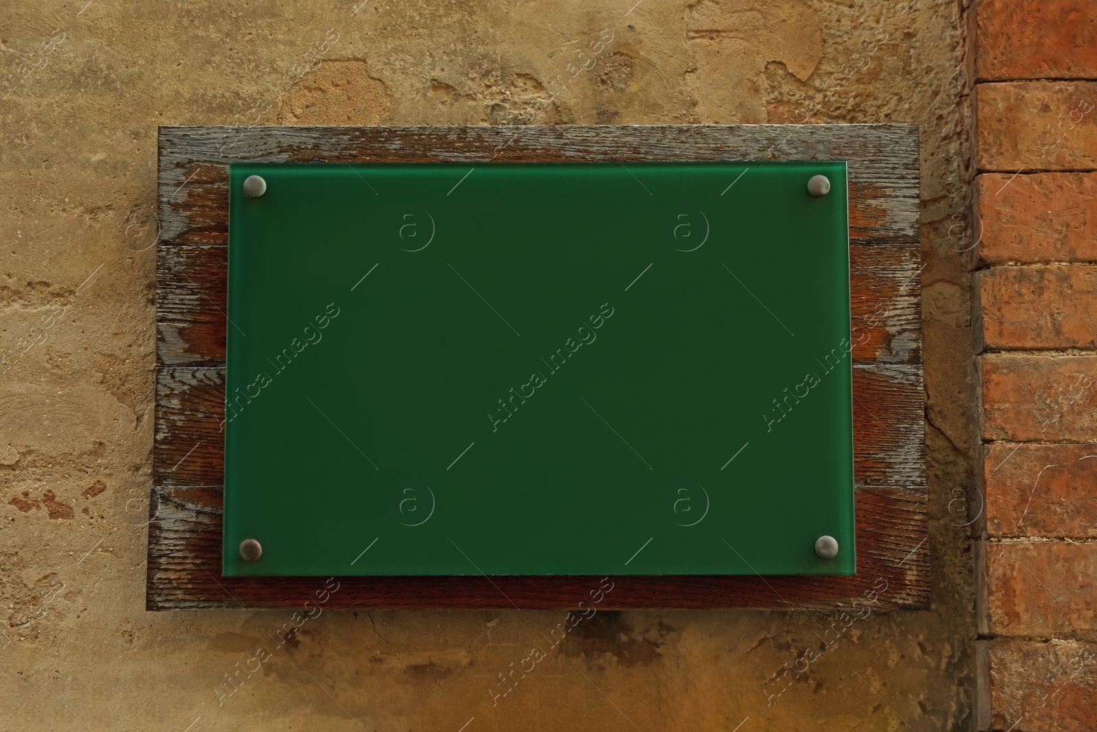 Photo of Blank green sign attached to brick wall. Space for design
