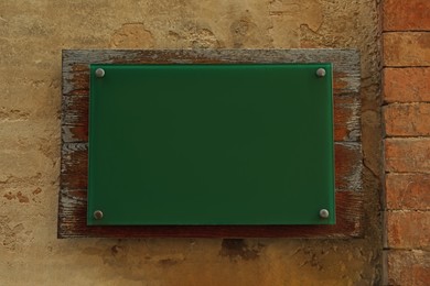 Blank green sign attached to brick wall. Space for design