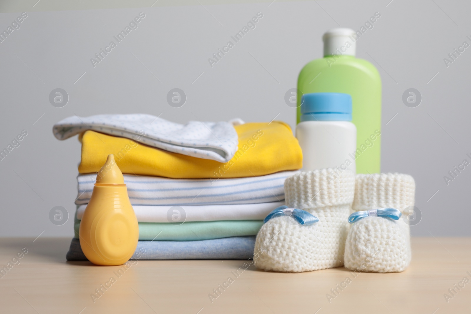 Photo of Baby clothes, booties and accessories on wooden table