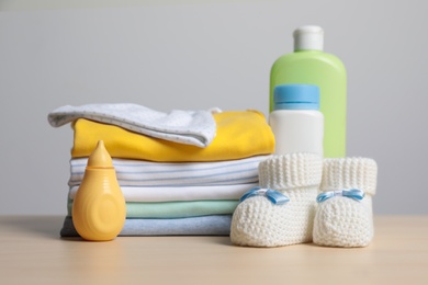 Baby clothes, booties and accessories on wooden table