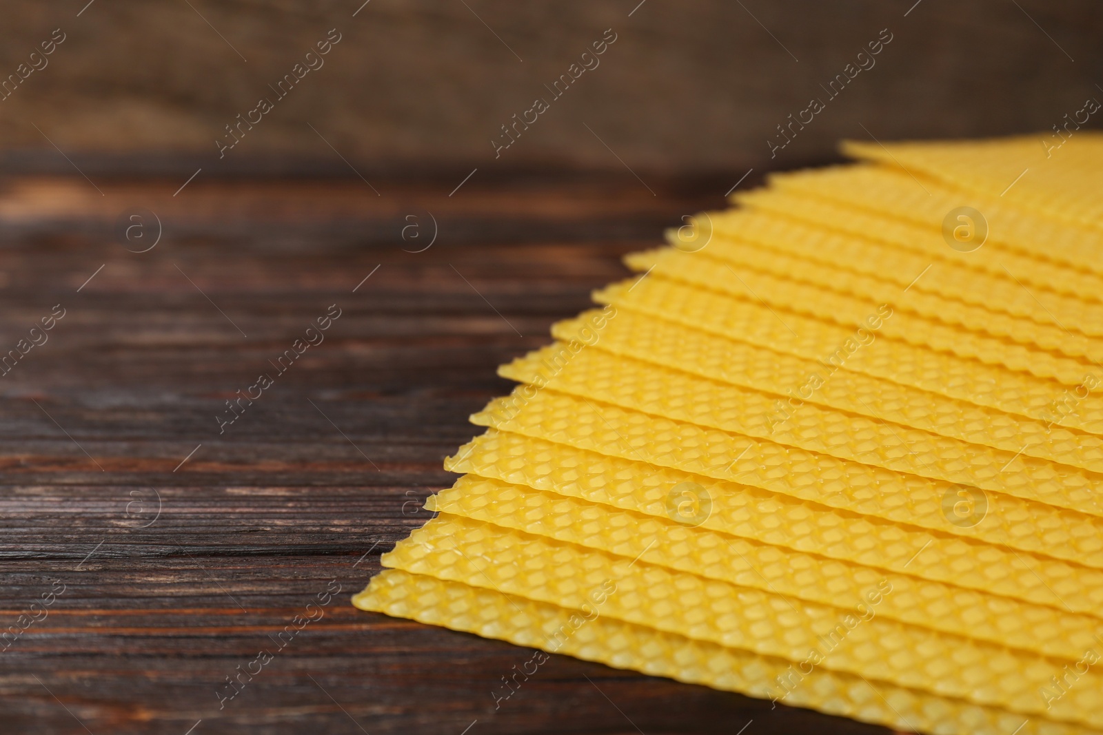 Photo of Natural beeswax sheets on wooden table, closeup. Space for text