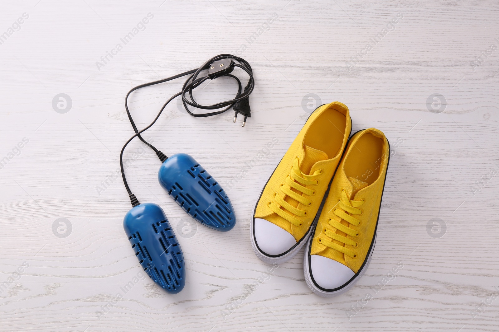 Photo of Shoes and electric dryer on white wooden background, flat lay