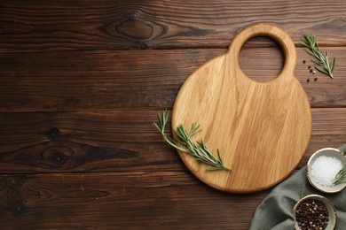 Photo of Cutting board, salt, pepper and rosemary on wooden table, flat lay. Space for text