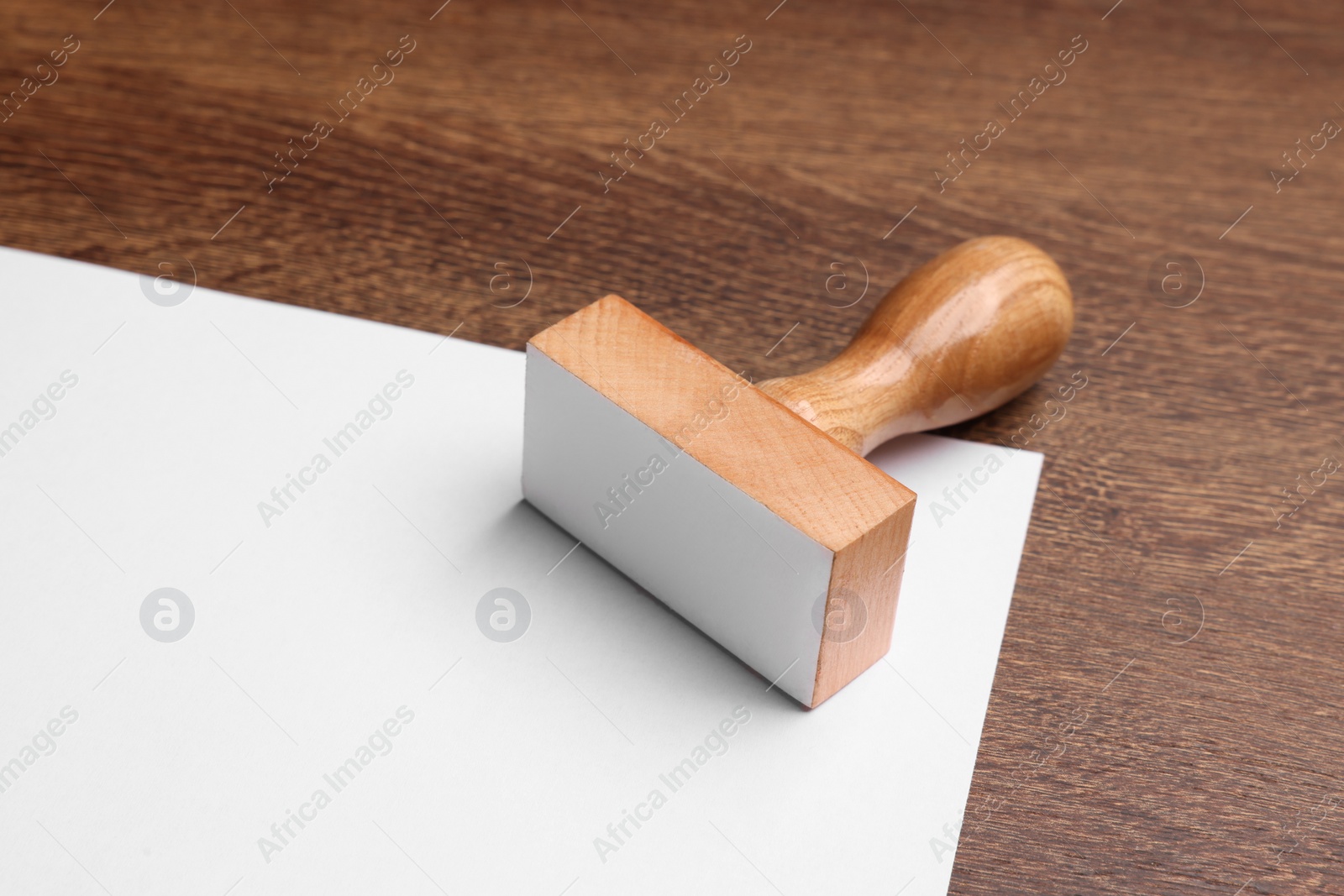 Photo of One stamp tool and sheet of paper on wooden table, closeup. Space for text