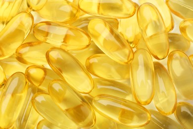 Yellow vitamin capsules as background, top view