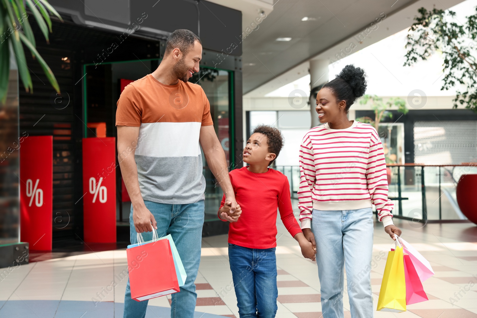 Photo of Family shopping. Happy parents and son with colorful bags in mall