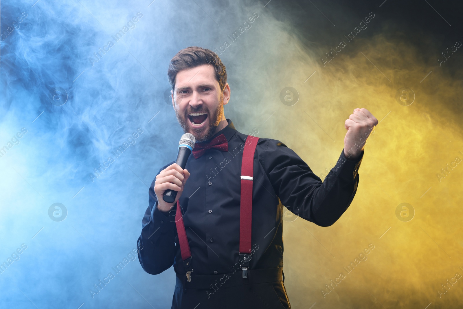 Photo of Emotional man with microphone singing in color lights