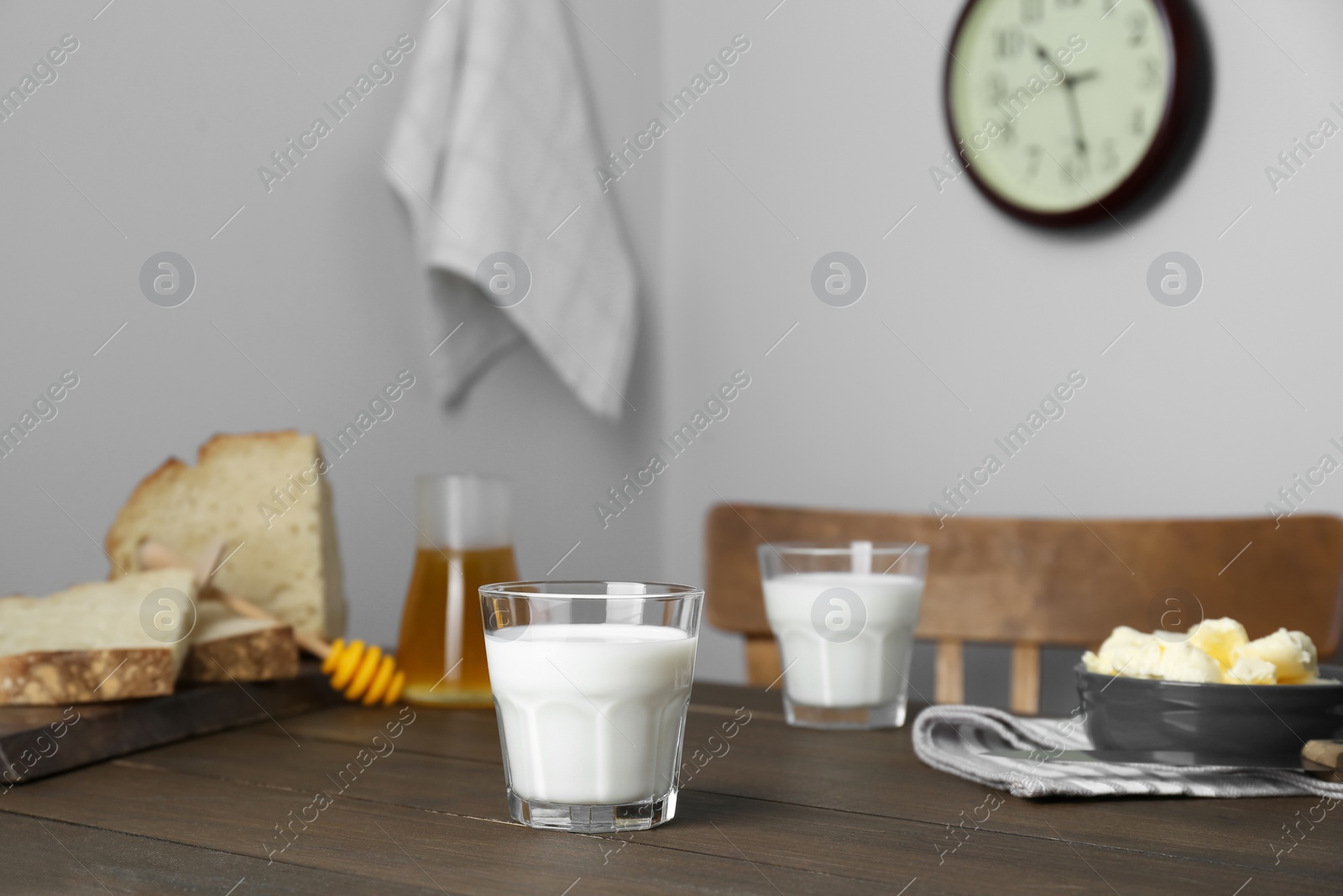 Photo of Delicious milk, honey, butter and bread served for breakfast on wooden table