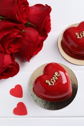 Photo of St. Valentine's Day. Delicious heart shaped cakes and beautiful roses on white wooden table, above view