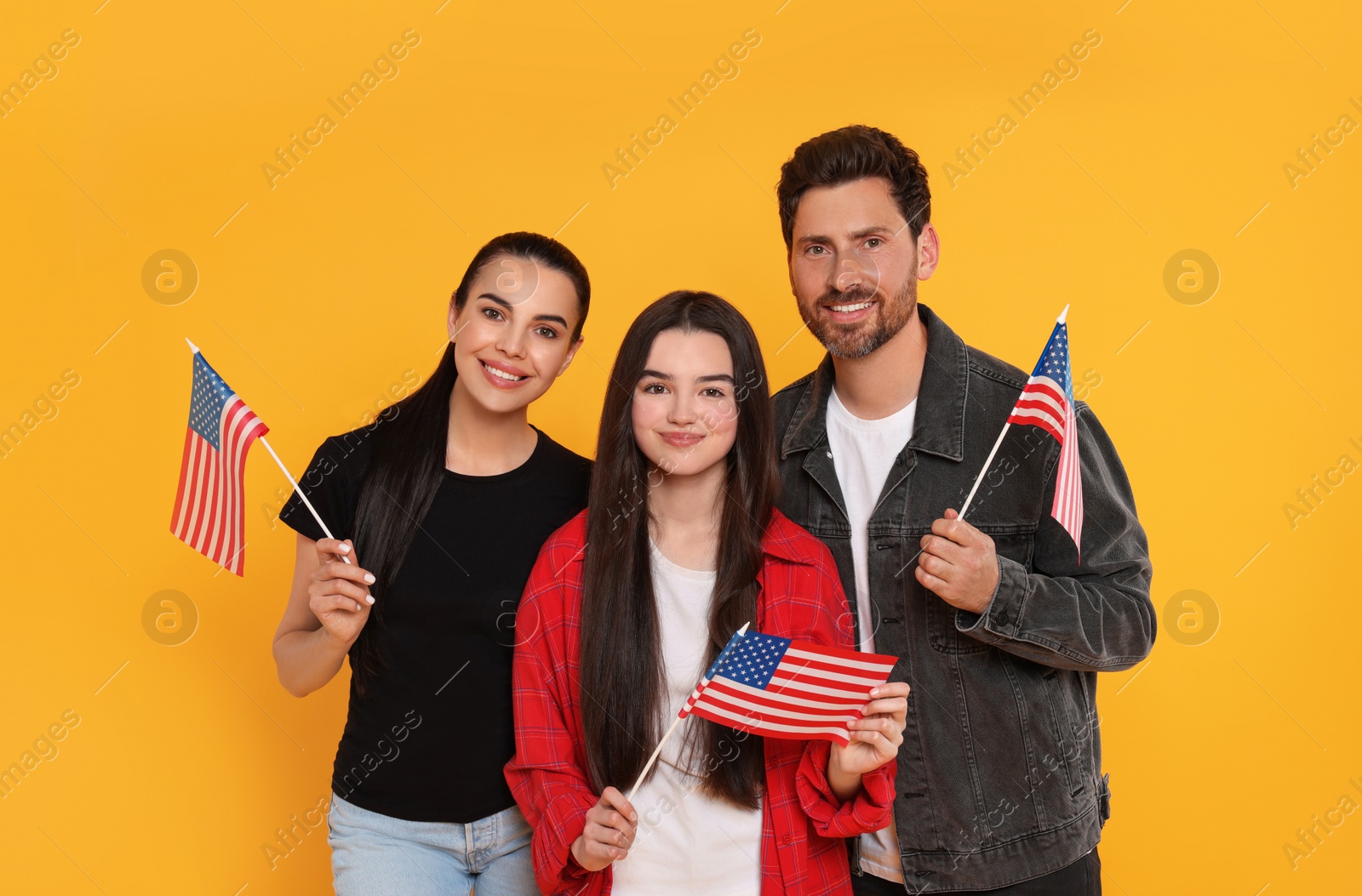 Photo of 4th of July - Independence Day of USA. Happy family with American flags on yellow background