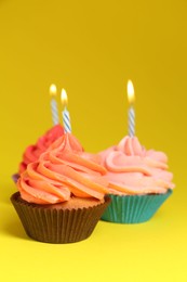 Photo of Delicious birthday cupcakes with bright cream on yellow background