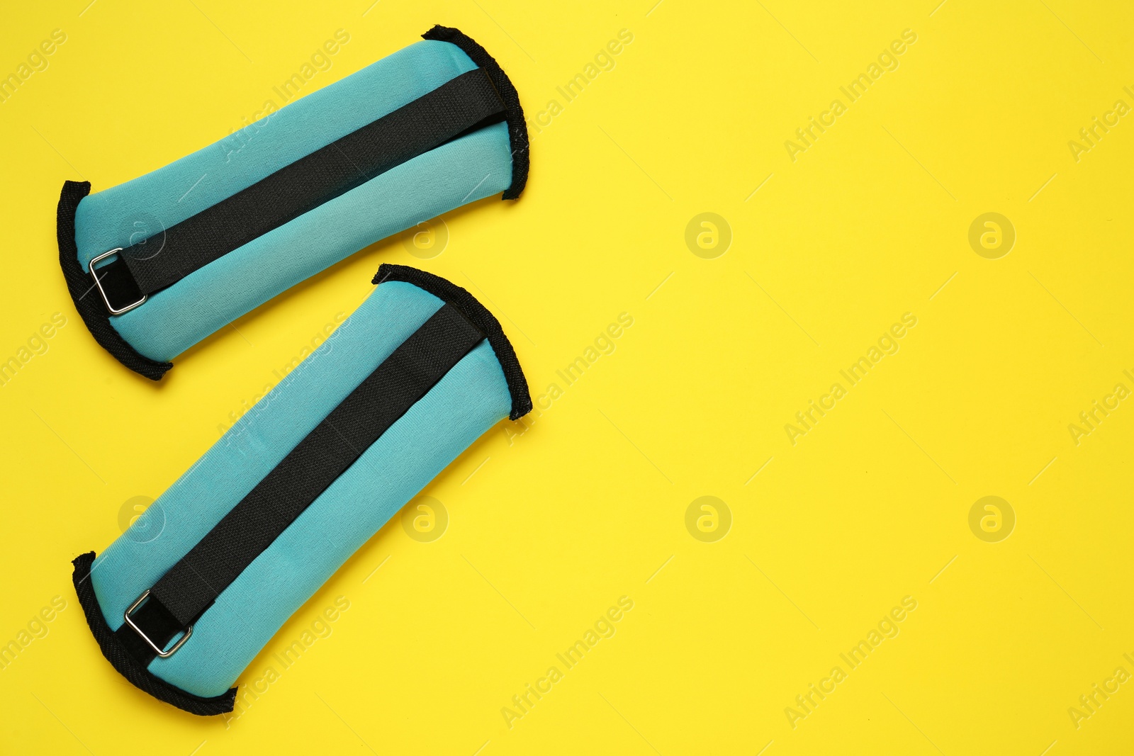 Photo of Turquoise weighting agents on yellow background, flat lay. Space for text