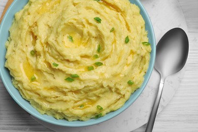 Photo of Bowl of tasty mashed potatoes with onion served on white wooden table, above view