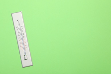 Weather thermometer on green background, top view. Space for text